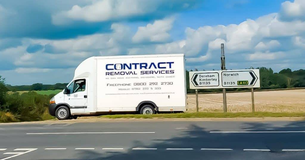Our removals van parked next to a sign pointing to Norwich and Dereham, Norfolk.